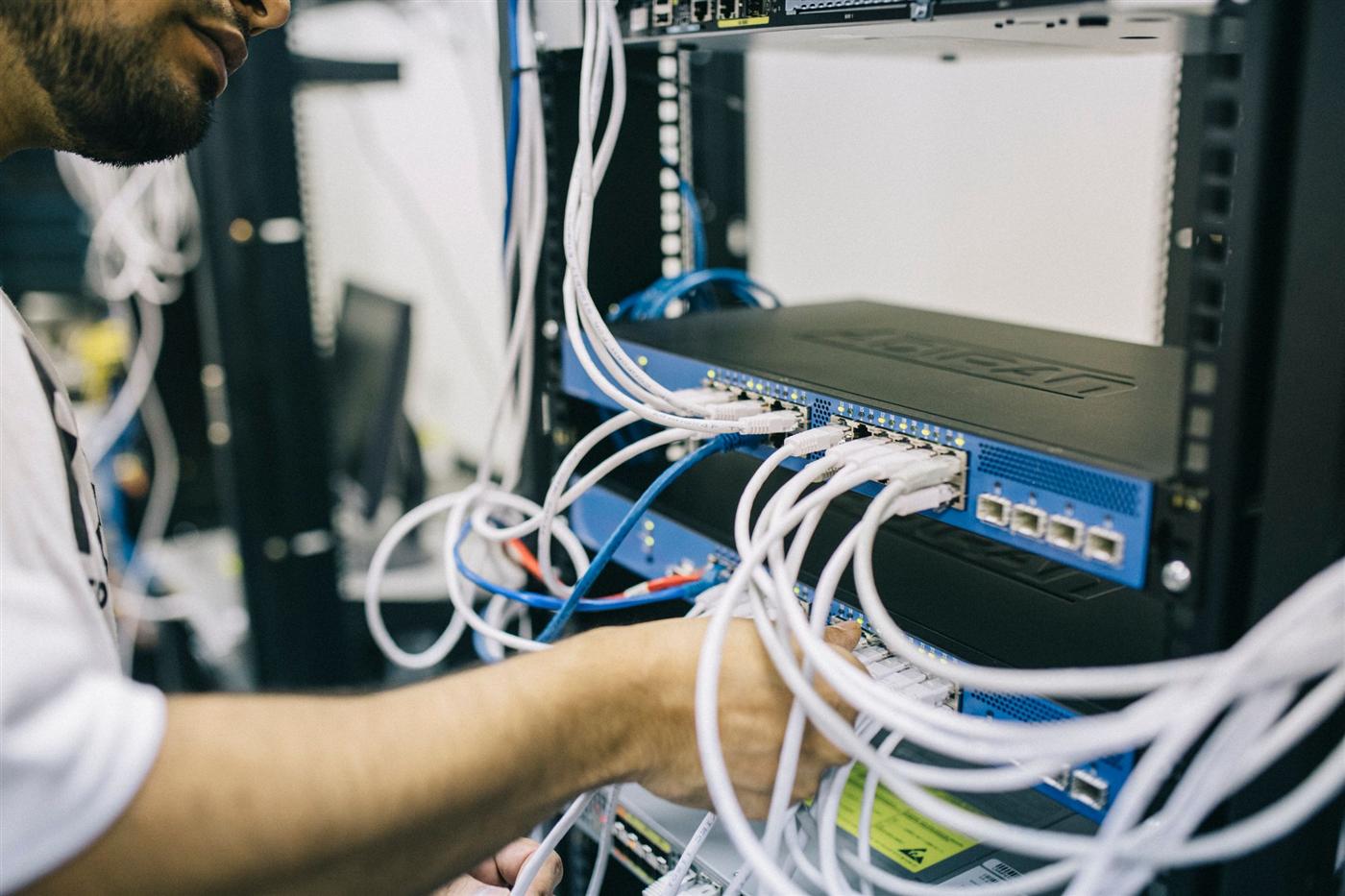 Technician connecting network cabling in a server rack